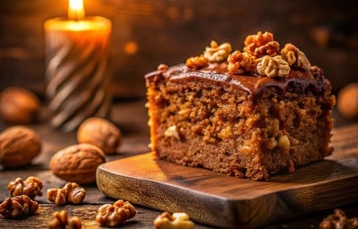 Fotografia de um pedaço de bolo rico e úmido, coberto com uma camada brilhante de chocolate, decorado com nozes inteiras, em um ambiente acolhedor com uma vela ao fundo. Fotografia de um pedaço de bolo rico e úmido, coberto com uma camada brilhante de chocolate, decorado com nozes inteiras, em um ambiente acolhedor com uma vela ao fundo.