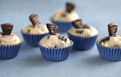 Fotografia em tons de azul e bege, mostrando seis docinhos decorados com pedaços de biscoito e tudo sobre bancada na cor azul.
