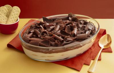 Foto da receita de Torta Alemã. Observa-se um refratário de vidro transparente com a torta decorada de raspas de limão sobre um guardanapo de pano vermelho.