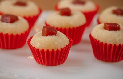 Fotografia de sete unidades de forminhas vermelhas com brigadeiro de romeu e julieta. Por cima de cada um tem um quadradinho de goiabada, e todos estão sobre um apoio decorativo de cor branca. Fotografia de sete unidades de forminhas vermelhas com brigadeiro de romeu e julieta. Por cima de cada um tem um quadradinho de goiabada, e todos estão sobre um apoio decorativo de cor branca.