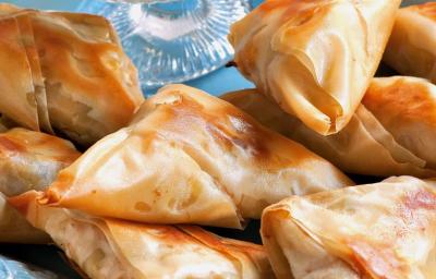 fotografia em tons de azul e bege tirada de uma prato quadrado azul com Samosas de massa filo. fotografia em tons de azul e bege tirada de uma prato quadrado azul com Samosas de massa filo.