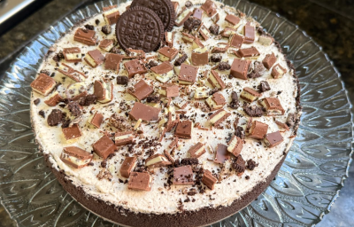 A imagem mostra uma torta redonda com uma camada de chocolate escuro por baixo e uma camada clara por cima.