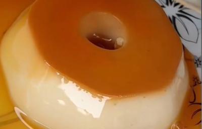 Fotografia de um mini pudim com calda sobre um prato branco com desenhos de cor preta. Fotografia de um mini pudim com calda sobre um prato branco com desenhos de cor preta.