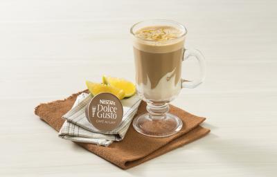 fotografia em tons de branco e marrom tirada de frente, contém um pano marrom com uma xicara transparente com a bebida de NESCAFÉ Dolce Gusto Café Au Lait com NESTLÉ Creme de Leite. Ao lado uma cápsula de Dolce Gusto e ao fundo fatias de laranja fotografia em tons de branco e marrom tirada de frente, contém um pano marrom com uma xicara transparente com a bebida de NESCAFÉ Dolce Gusto Café Au Lait com NESTLÉ Creme de Leite. Ao lado uma cápsula de Dolce Gusto e ao fundo fatias de laranja