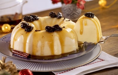 Imagem de um prato com a receita de manjar com calda de ameixa e uma espátula tirando um pedaço.