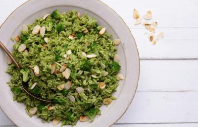 Fotografia em tons de verde em uma bancada de madeira com um prato redondo fundo com o arroz de brócolis e lascas de amêndoas. Fotografia em tons de verde em uma bancada de madeira com um prato redondo fundo com o arroz de brócolis e lascas de amêndoas.