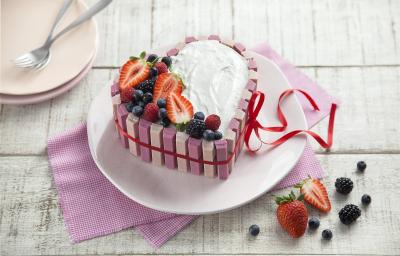 fotografia em tons de branco e rosa de uma bancada branca vista de cima, ao centro um pano rosa com um prato redondo por cima um bolo em formato de coração com marshmallow, morangos e frutas vermelhas por cima para decorar. fotografia em tons de branco e rosa de uma bancada branca vista de cima, ao centro um pano rosa com um prato redondo por cima um bolo em formato de coração com marshmallow, morangos e frutas vermelhas por cima para decorar.