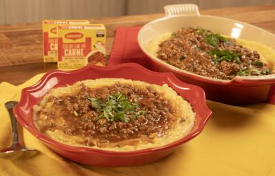 Fotografia mostra dois refratários vermelhos servidos com polenta e molho de carne por cima