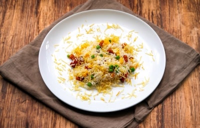 Em um prato branco redondo, porção de arroz com ervilha, pedaços de bacon e batata palha. Em um prato branco redondo, porção de arroz com ervilha, pedaços de bacon e batata palha.