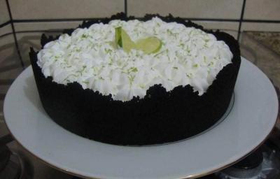 Foto da receita de Torta de Limão com Biscoito. Observa-se uma torta com base escura de chocolate em um prato branco.