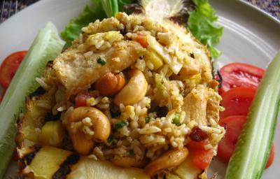 Fotografia de arroz com castanhas, com tomate e pepino decorando ao lado, dentro de um prato branco.