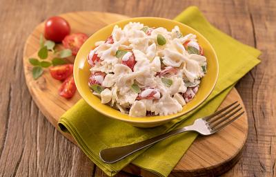 Foto da receita de saladinha de macarrão no copinho servida em um copo largo amarelo sobre um paninho verde com um garfo prateado ao lado, há também, em cima da tábua de madeira, tomates cerejas cortados ao meio Foto da receita de saladinha de macarrão no copinho servida em um copo largo amarelo sobre um paninho verde com um garfo prateado ao lado, há também, em cima da tábua de madeira, tomates cerejas cortados ao meio