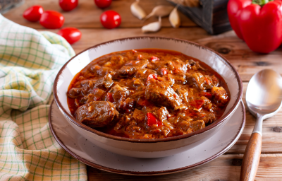 Ensopado de carne macia envolta em um molho avermelhado e espesso, servido em um prato fundo com salsinha picada por cima Ensopado de carne macia envolta em um molho avermelhado e espesso, servido em um prato fundo com salsinha picada por cima