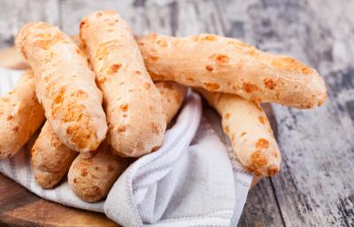 Fotografia em tons de cinza com uma toalha branca ao centro. Em cima da toalha existe vários biscoitinhos de polvilho dourados. Fotografia em tons de cinza com uma toalha branca ao centro. Em cima da toalha existe vários biscoitinhos de polvilho dourados.