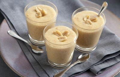 fotografia em tons de bege e cinza de uma bancada cinza vista de cima. Contém 3 copinhos com o creme de paçoca com amendoim por cima para decorar e abaixo um pano cinza. fotografia em tons de bege e cinza de uma bancada cinza vista de cima. Contém 3 copinhos com o creme de paçoca com amendoim por cima para decorar e abaixo um pano cinza.