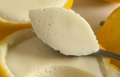 Fotografia de uma receita de mousse de limão siciliano que é servido dentro das cascas do próprio limão. No centro da foto tem uma colher segurando uma porção da mousse. Fotografia de uma receita de mousse de limão siciliano que é servido dentro das cascas do próprio limão. No centro da foto tem uma colher segurando uma porção da mousse.