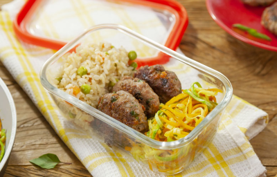 Fotografia em tons de amarelo em uma mesa de madeira com um pano de prato branco com listras amarelas, um potinho de marmita de vidro com o arroz integral, o mini hambúrguer e o macarrão de legumes Fotografia em tons de amarelo em uma mesa de madeira com um pano de prato branco com listras amarelas, um potinho de marmita de vidro com o arroz integral, o mini hambúrguer e o macarrão de legumes