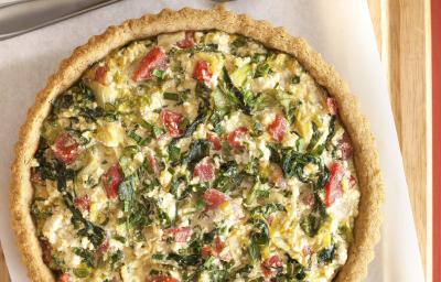 fotografia em tons de bege, branco e verde tirada de uma tábua de madeira com um pano branco, e por cima uma torta com escarola . fotografia em tons de bege, branco e verde tirada de uma tábua de madeira com um pano branco, e por cima uma torta com escarola .