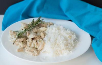 A imagem mostra um prato montado com arroz e tiras de frango com molho, decorado com alecrim