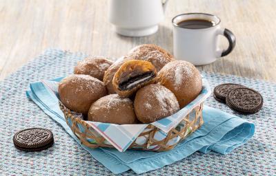 Imagem de uma cesta com bolinhos de chuva recheados com Negresco. Ao lado, biscoitos Negresco e uma xícara de café. Imagem de uma cesta com bolinhos de chuva recheados com Negresco. Ao lado, biscoitos Negresco e uma xícara de café.