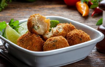 Fotografia em tons de branco com um prato fundo e branco ao centro. Dentro do prato existe vários bolinhos de bacalhau feitos na Air Fryer acompanhados por fatias de limão Fotografia em tons de branco com um prato fundo e branco ao centro. Dentro do prato existe vários bolinhos de bacalhau feitos na Air Fryer acompanhados por fatias de limão