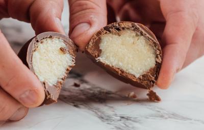Foto da receita de Bombom de Prestígio. Observa-se uma foto bem perto do bombom cortado ao meio, expondo o recheio cremoso de coco. Foto da receita de Bombom de Prestígio. Observa-se uma foto bem perto do bombom cortado ao meio, expondo o recheio cremoso de coco.