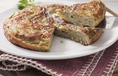 Fotografia em tons de marrom em uma bancada de madeira com um jogo americano vinho com um prato raso branco com a omelete recheada em cima dele. Fotografia em tons de marrom em uma bancada de madeira com um jogo americano vinho com um prato raso branco com a omelete recheada em cima dele.