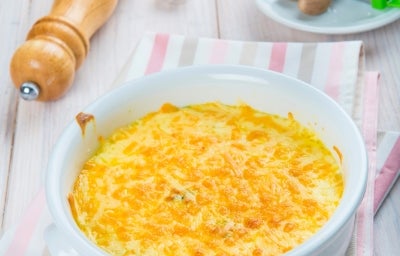 Fotografia em tons de branco com um gratinado ao centro. O gratinado é feito com Brócolis e NINHO Adulto Fotografia em tons de branco com um gratinado ao centro. O gratinado é feito com Brócolis e NINHO Adulto