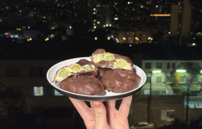 imagem mostra vários bombons de chocolate, um cortado ao meio com um creme branco e uma verde recheado