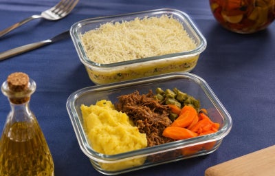 Fotografia de duas marmitas de vidro com receitas de escondidinho de frango e também de carne desfiada com legumes