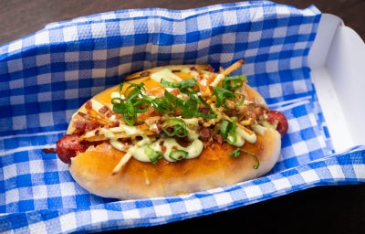 Cachorro-quente gourmet com linguiça artesanal, pão caseiro, maionese verde, batata palha e bacon crocante