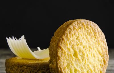 Fotografia de um biscoito em pé apoiado em outros dois biscoitos que estão atrás, e em cima desses que estão empilhados, tem uma lasca pequena de queijo. Estão sobre uma mesa de madeira em tons de cinza. Fotografia de um biscoito em pé apoiado em outros dois biscoitos que estão atrás, e em cima desses que estão empilhados, tem uma lasca pequena de queijo. Estão sobre uma mesa de madeira em tons de cinza.