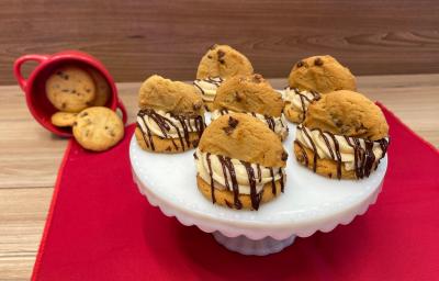 Fotografia mostra cookies cobertos por um creme branco e chocolate derretido, e meio cookie no topo.