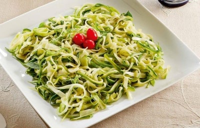 Prato quadrado branco com macarrão de abobrinha em tiras com manjericão decorado com tomates cereja. Prato quadrado branco com macarrão de abobrinha em tiras com manjericão decorado com tomates cereja.