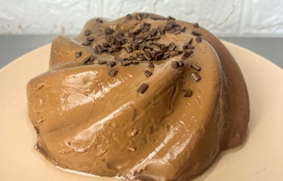 Fotografia em tons claros com um manjar de chocolate meio amargo ao centro.