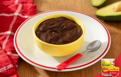 Mousse de chocolate em tigela amarela sobre prato branco com NINHO® Primeira Infância.