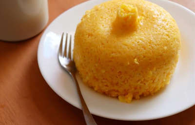 Imagem de um bolinho de milho em formato redondo com um bico na ponta, em tons de amarelo, dourado e marrom. Imagem de um bolinho de milho em formato redondo com um bico na ponta, em tons de amarelo, dourado e marrom.