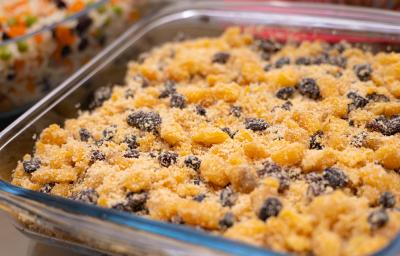 Fotografia de uma travessa de vidro quadrada com uma farofa de frutas deliciosa feita com farinha de mandioca com pêssego em calda, ameixa seca, uva-passa e MAGGI Fondor.