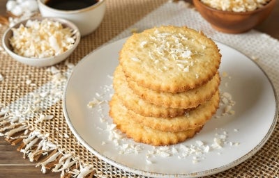 Em cima de uma mesa prato redondo, com biscoitos amanteigados enfileirados, decorado com coco ralado. Em cima de uma mesa prato redondo, com biscoitos amanteigados enfileirados, decorado com coco ralado.