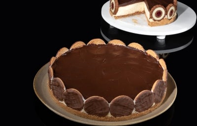 Em cima de uma mesa, prato redondo com torta de biscoitos calipso, com ganache de chocolate.