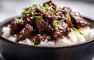 imagem mostra um cozido de carne servido junto de arroz branco e cebolinhas verdes picadas