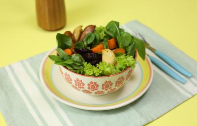 Fotografia em tons de amarelo em uma bancada de madeira amarela, um jogo americano verde claro listrado, um prato branco com listas coloridas, um potinho branco com flores e dentro uma salada de legumes. Fotografia em tons de amarelo em uma bancada de madeira amarela, um jogo americano verde claro listrado, um prato branco com listas coloridas, um potinho branco com flores e dentro uma salada de legumes.