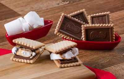 Fotografia em tons de vermelho com vários recipientes vermelhos ao centro. Dentro de um dos recipientes, existe dois biscoitos Choco Biscuit recheados com marsmallow. Ao lado existe marshmallows e biscoitos Choco Biscuit NESTLÉ Fotografia em tons de vermelho com vários recipientes vermelhos ao centro. Dentro de um dos recipientes, existe dois biscoitos Choco Biscuit recheados com marsmallow. Ao lado existe marshmallows e biscoitos Choco Biscuit NESTLÉ