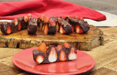 Fotografia de uma barrade chocolate com morango sobre uma superfície de madeira.