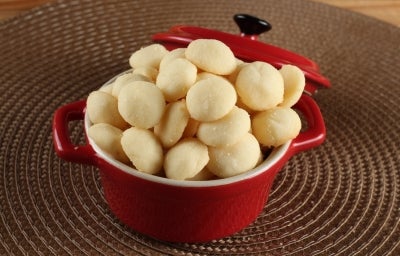 Em cima de uma mesa, recipiente redondo com biscoitos amanteigados redondos e dourados. Em cima de uma mesa, recipiente redondo com biscoitos amanteigados redondos e dourados.