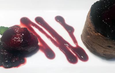 Fotografia de um flan de chocolate sobre um prato branco com uma calda de frutas vermelhas e pequenas folhas de hortelãs. Fotografia de um flan de chocolate sobre um prato branco com uma calda de frutas vermelhas e pequenas folhas de hortelãs.
