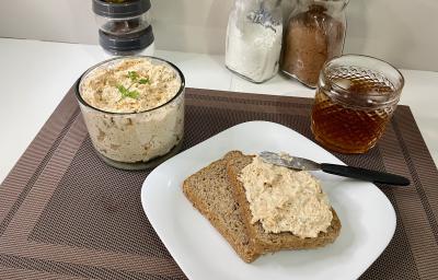 Imagem da receita de Patê de Frango em um prato branco sobre um pano, ao lado uma bebida e um copo com o patê