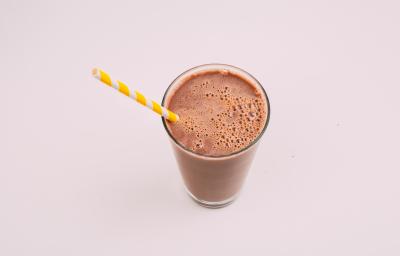fotografia em tons de marrom tirada de um copo transparente, com uma bebida de chocolate gelada e um canudo branco e amarelo para servir. fotografia em tons de marrom tirada de um copo transparente, com uma bebida de chocolate gelada e um canudo branco e amarelo para servir.