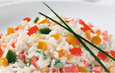 Fotografia em tons de branco e multicoloridos, porcelana branca com porção de arroz com legumes picados e decorados com duas folhas de cebolinha-verde, dois guardanapos brancos ao lado, tudo sobre bancada branca. Fotografia em tons de branco e multicoloridos, porcelana branca com porção de arroz com legumes picados e decorados com duas folhas de cebolinha-verde, dois guardanapos brancos ao lado, tudo sobre bancada branca.