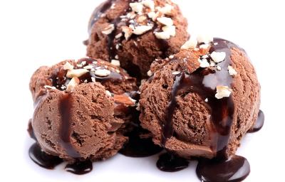 Fotografia de três bolas de sorvete de chocolate com cobertura de chocolate e farofa doce. A sobremesa está em um fundo branco. Fotografia de três bolas de sorvete de chocolate com cobertura de chocolate e farofa doce. A sobremesa está em um fundo branco.